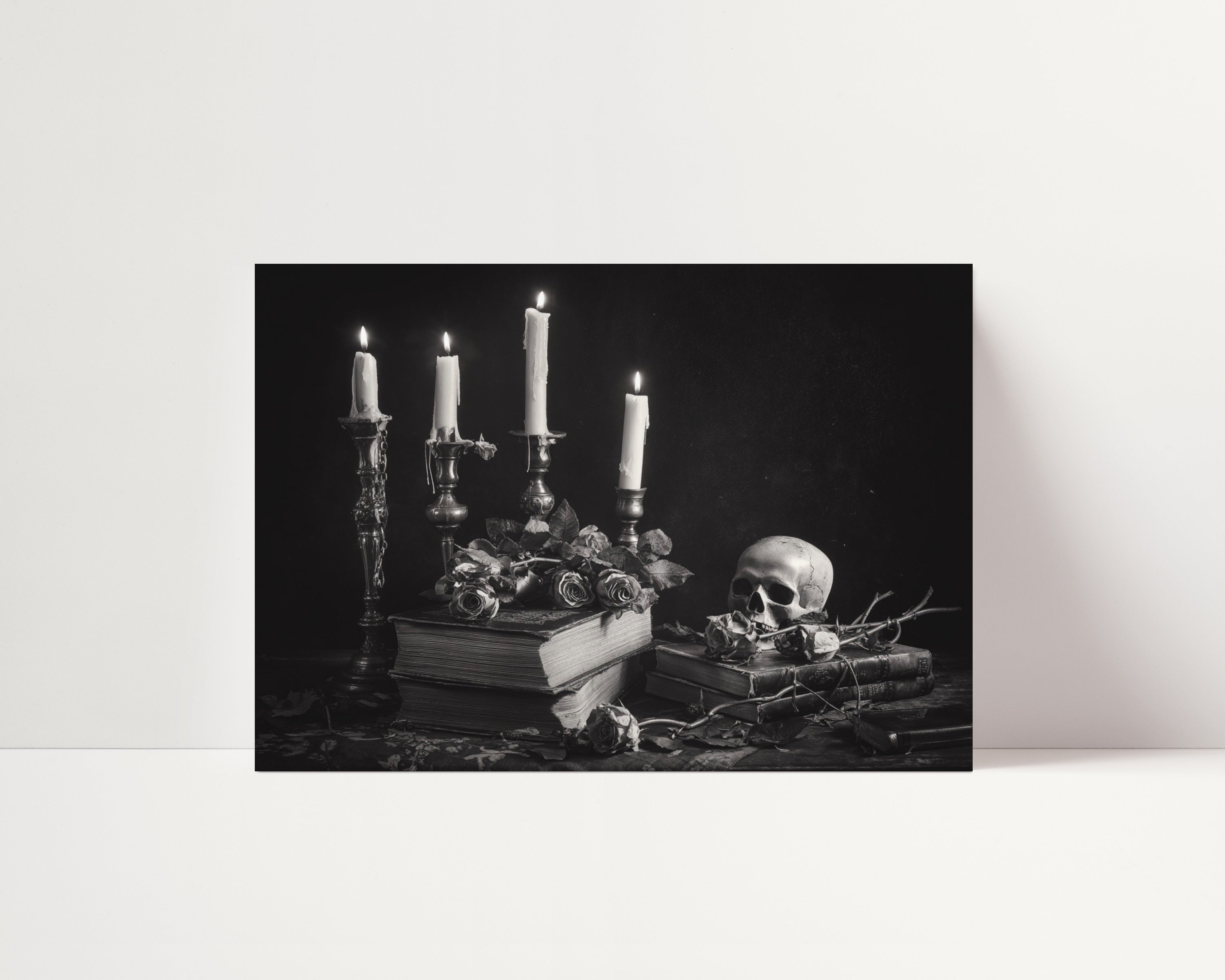 Black and white still life featuring lit taper candles in ornate holders, stacked vintage books, scattered roses, and a decorative skull, creating a dark, gothic-inspired composition with dramatic contrast and vintage atmosphere.