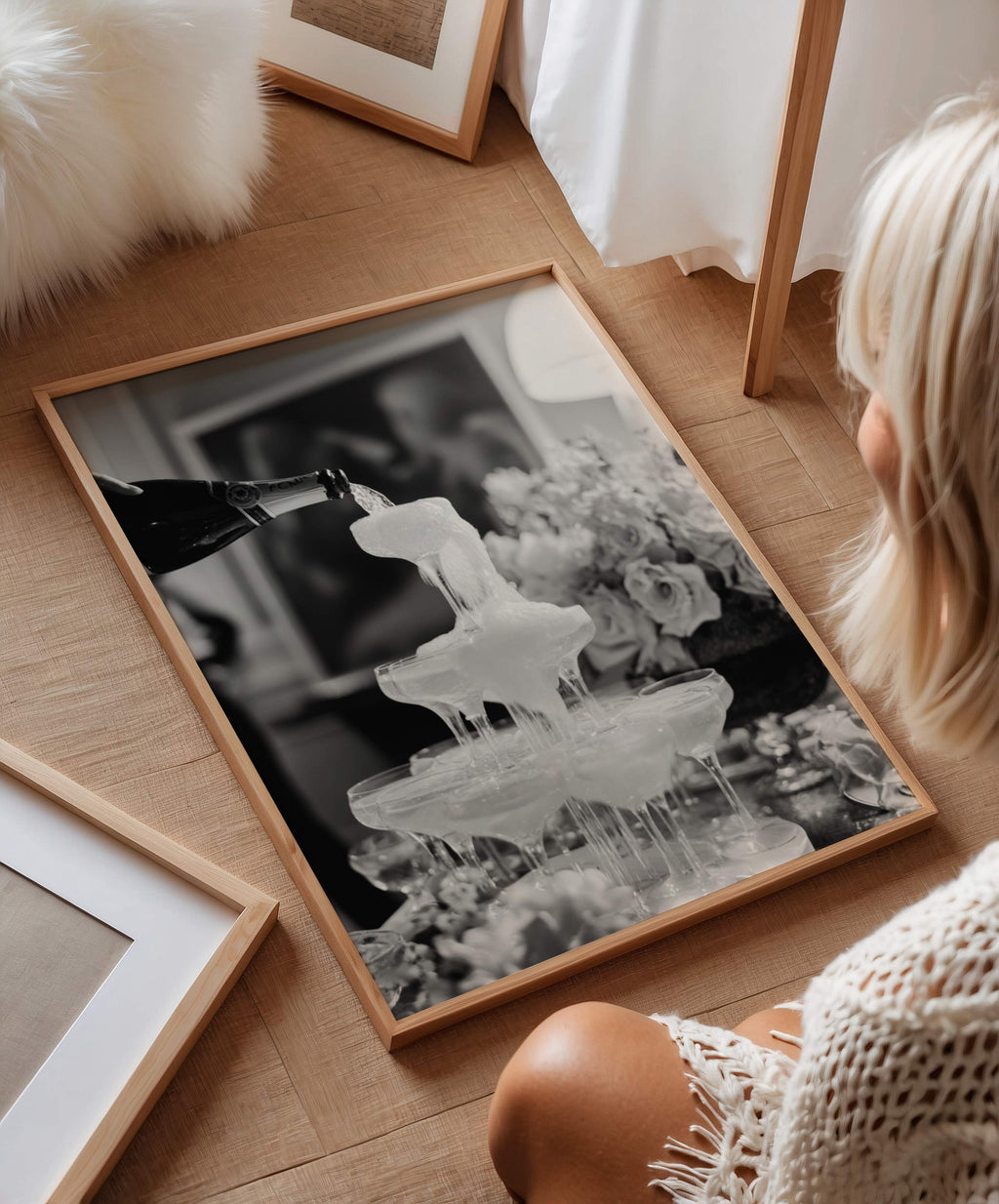 woman admiring black and white champagne shower wall art framed on the ground
