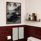 framed black and white French Riviera poster print hanging above toilet in bathroom with red tile