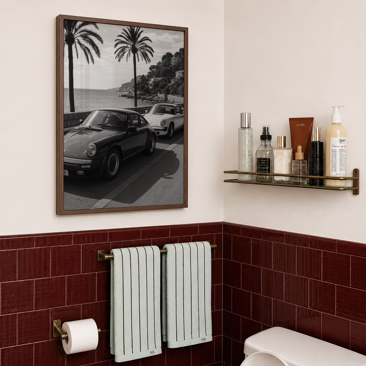 framed black and white French Riviera poster print hanging above toilet in bathroom with red tile