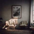 Cozy living room with two armchairs, a small table, and a framed French Rivera print on the wall.
