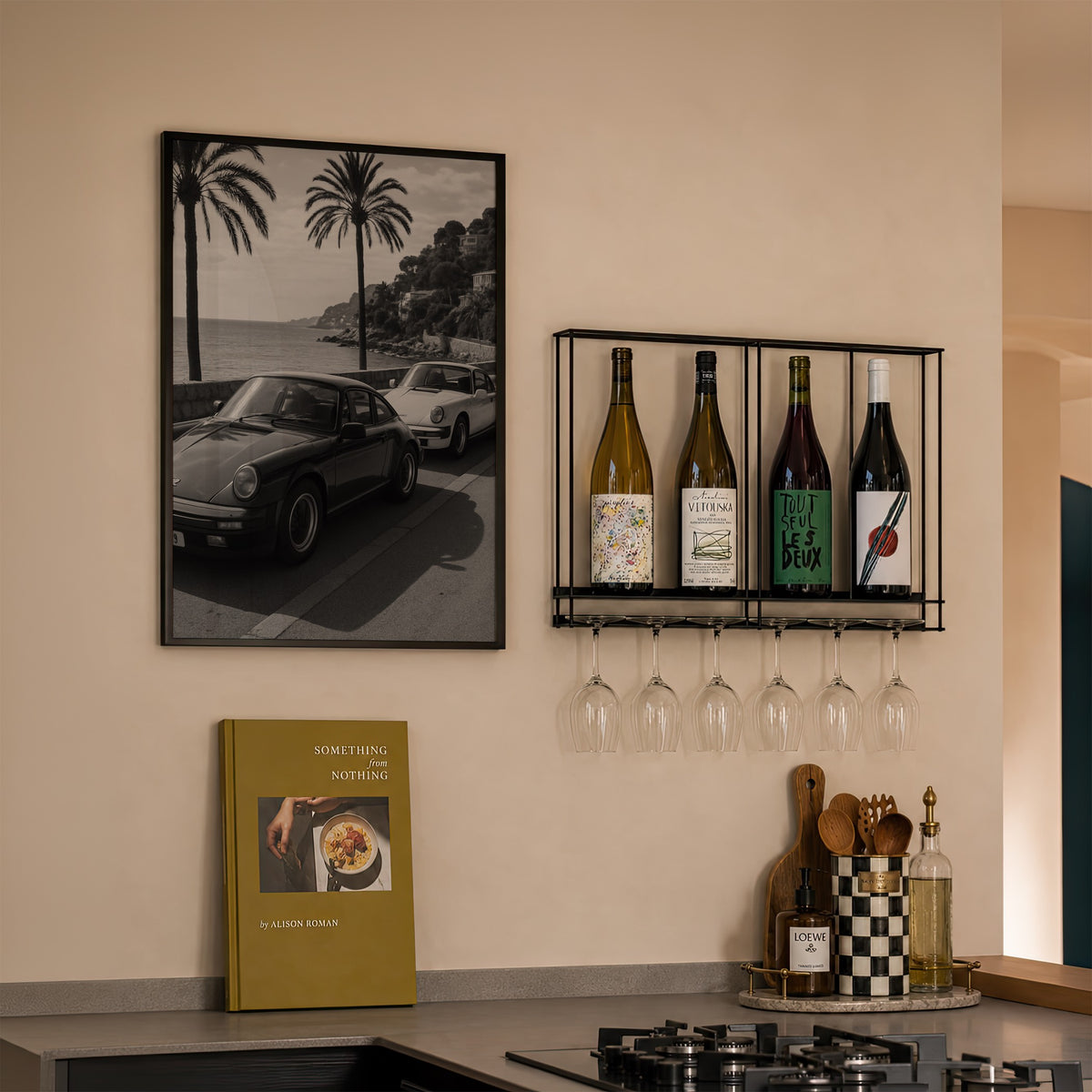 framed black and white French Riviera poster print hanging in kitchen next to wine rack and cook book