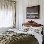 black and white framed western wall art hanging above bed in rustic bedroom
