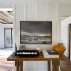 Modern interior with a wooden table, keyboard, and decorative items against a white wall with a framed black and white western wall art