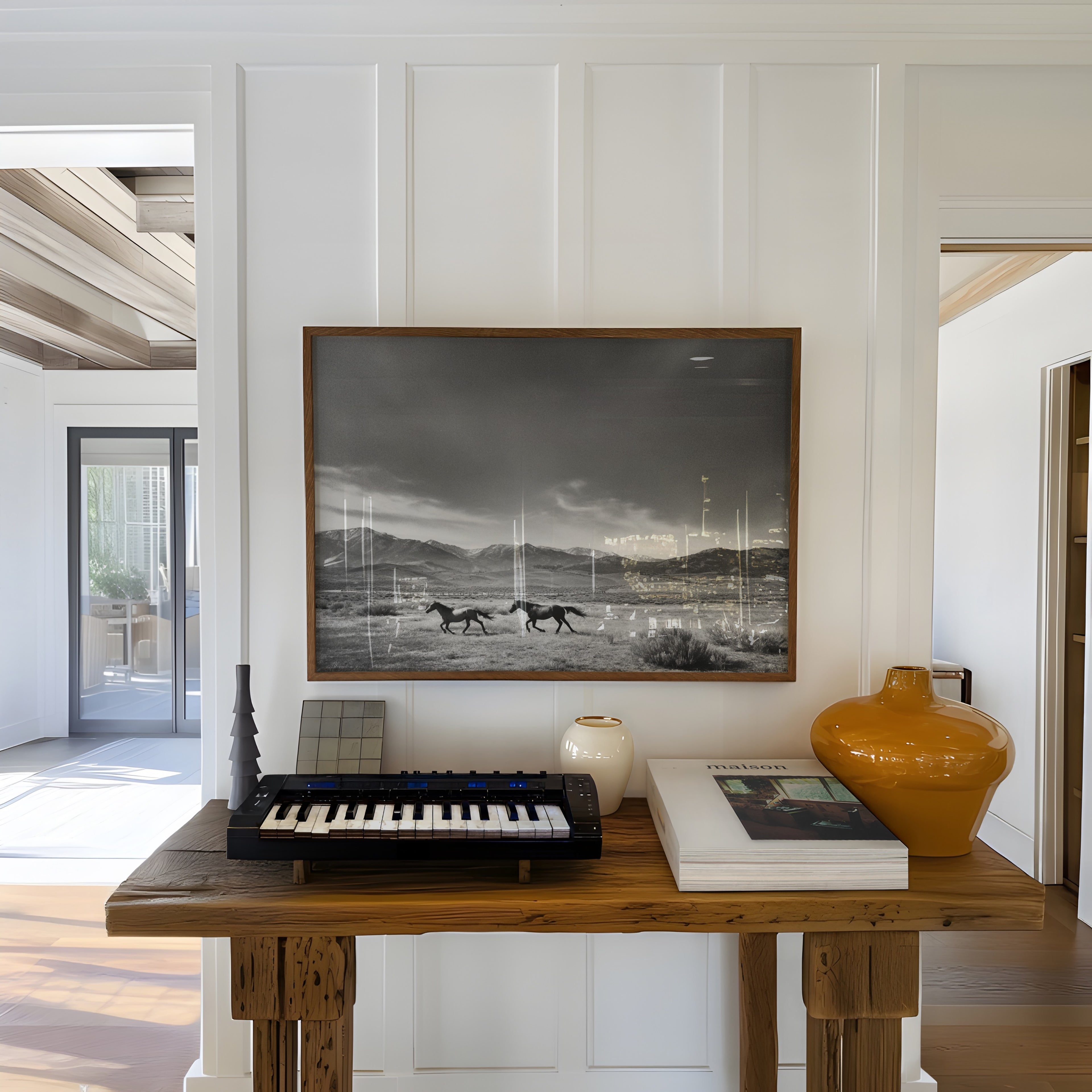 Modern interior with a wooden table, keyboard, and decorative items against a white wall with a framed black and white western wall art