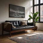 framed black and white wall art hanging above black leather couch in living room