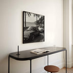 Modern interior with a black console table, stool, and framed black and white French Rivera artwork on a white wall.