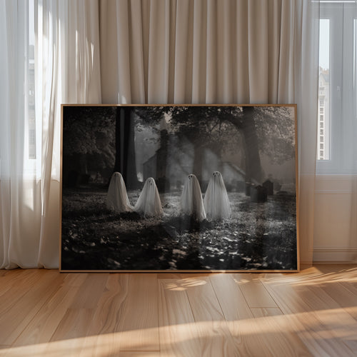 Framed black and white artwork of ghosts in a forest displayed on a wall.