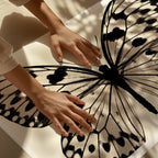 hands touching a large black and white poster print of butterly