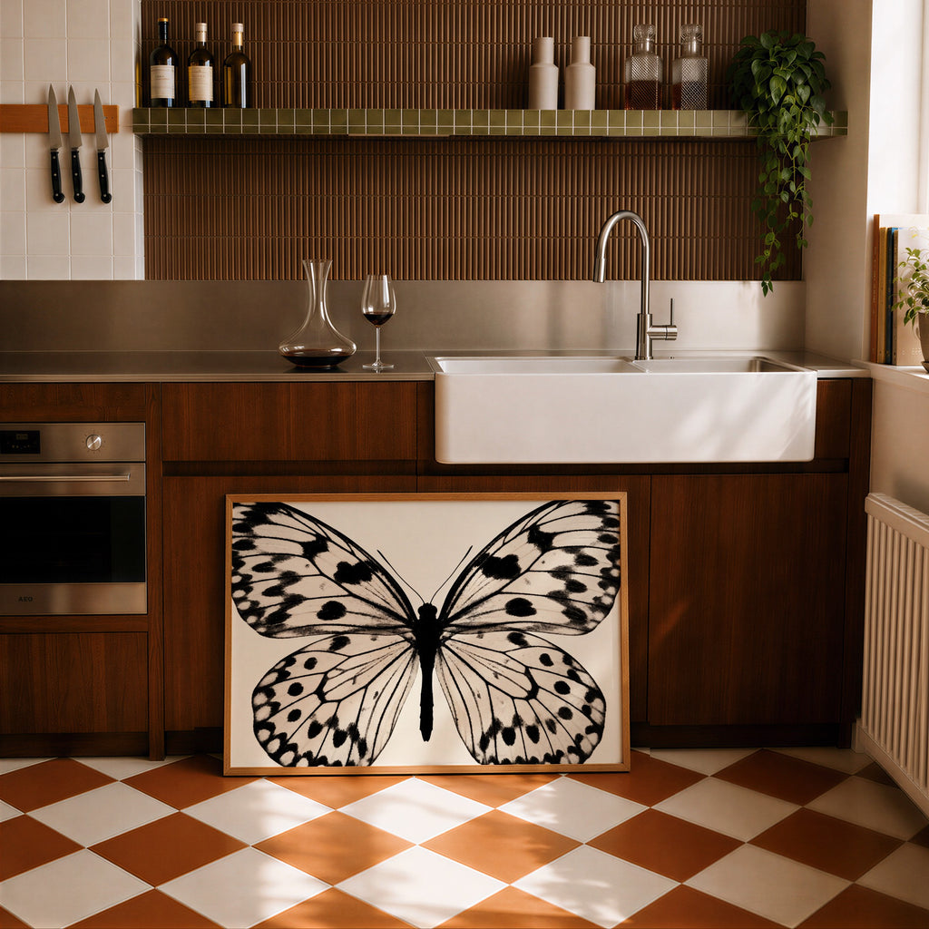framed butterfly poster print leaning against cabinets in a modern kitchen with wooden panels and modern finishes