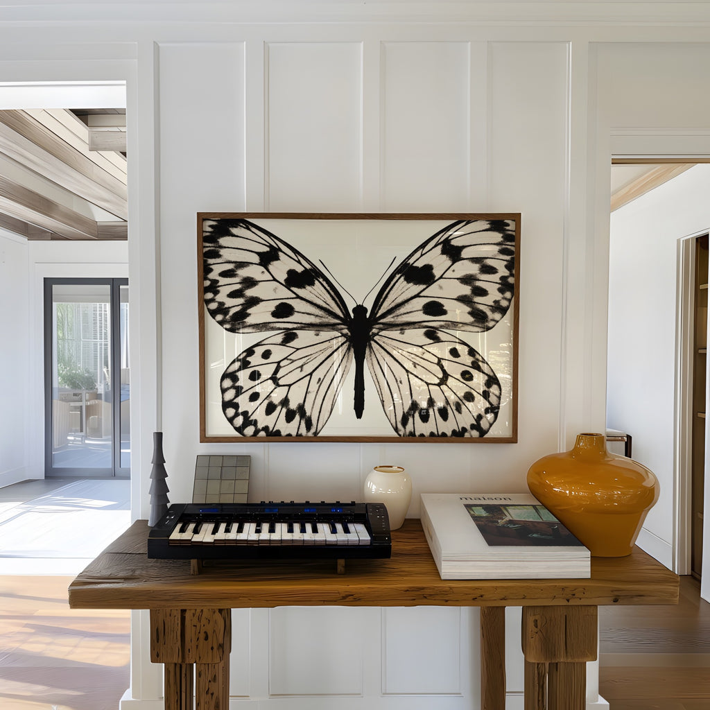 framed black and white poster print hanging in entryway over wooden table with decor and keyboard