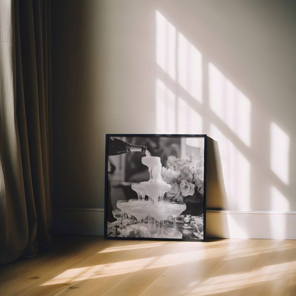 square framed black and white champagne showers poster print sitting on floor leaning against shadowed wall