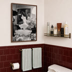 framed black and white champagne showers poster print hanging in bathroom with red tiles