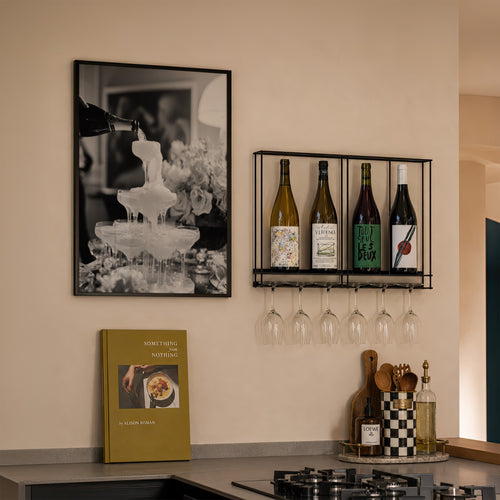 framed champagne showers black and white poster print hanging in kitchen next to wine rack above cook book