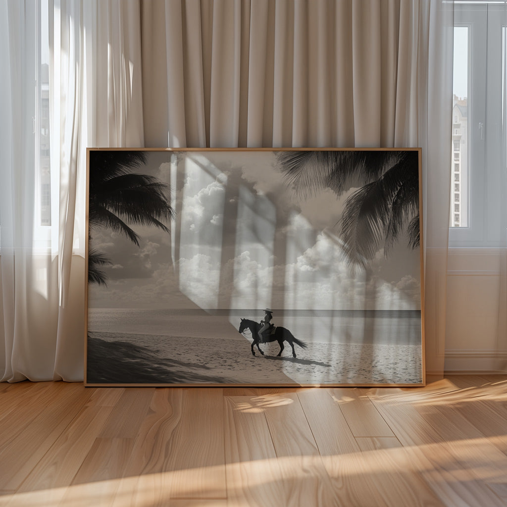 Framed artwork of a person riding a horse on a beach with palm trees, displayed in a room with curtains and wooden floor.