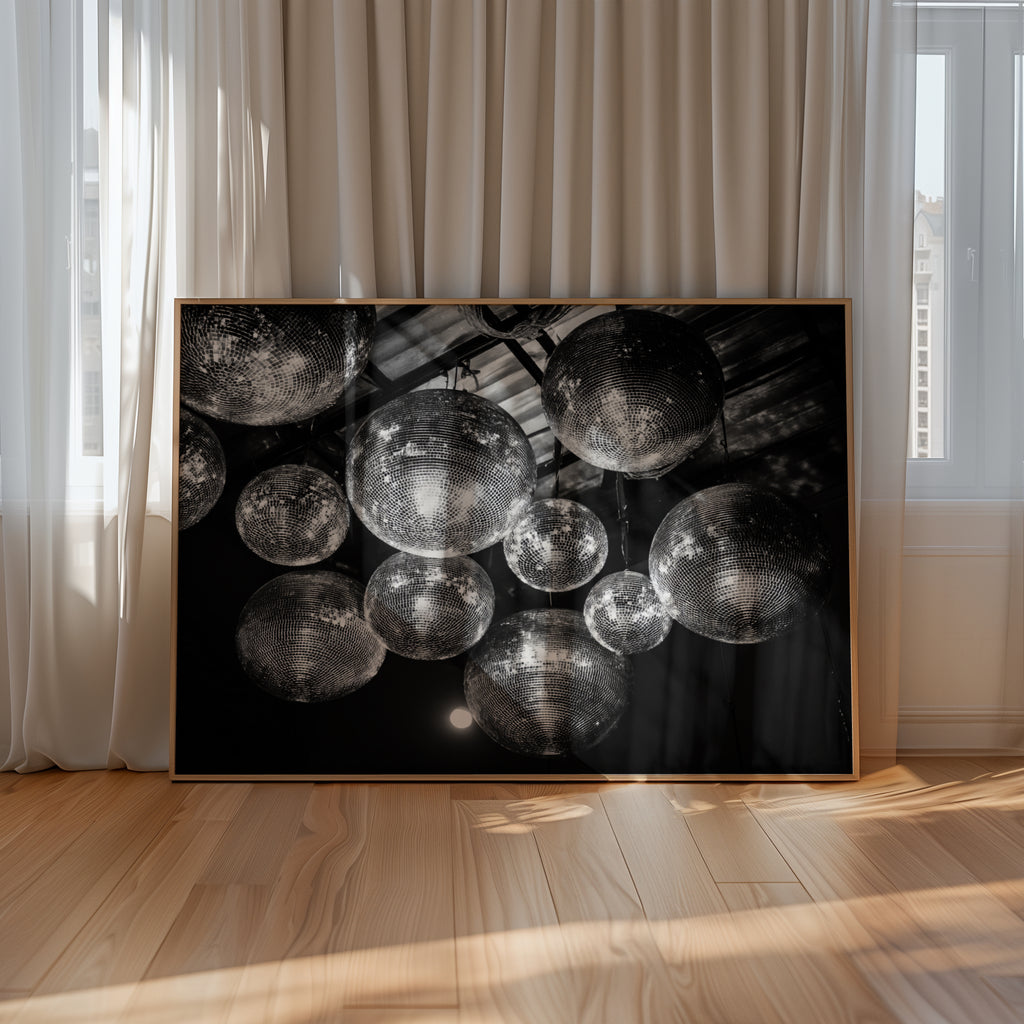 Framed black and white disco party wallet art on a wall with curtains and wooden floor.