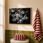 framed black and white disco ball poster print hanging above toilet in bathroom with green wall tiles 
