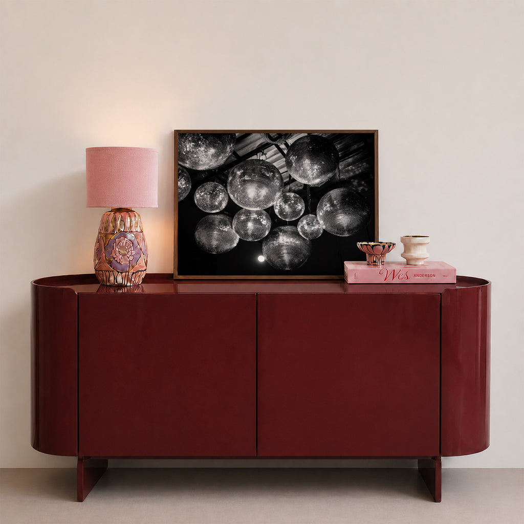 framed black and white disco ball poster print on red console with pink decor in entryway