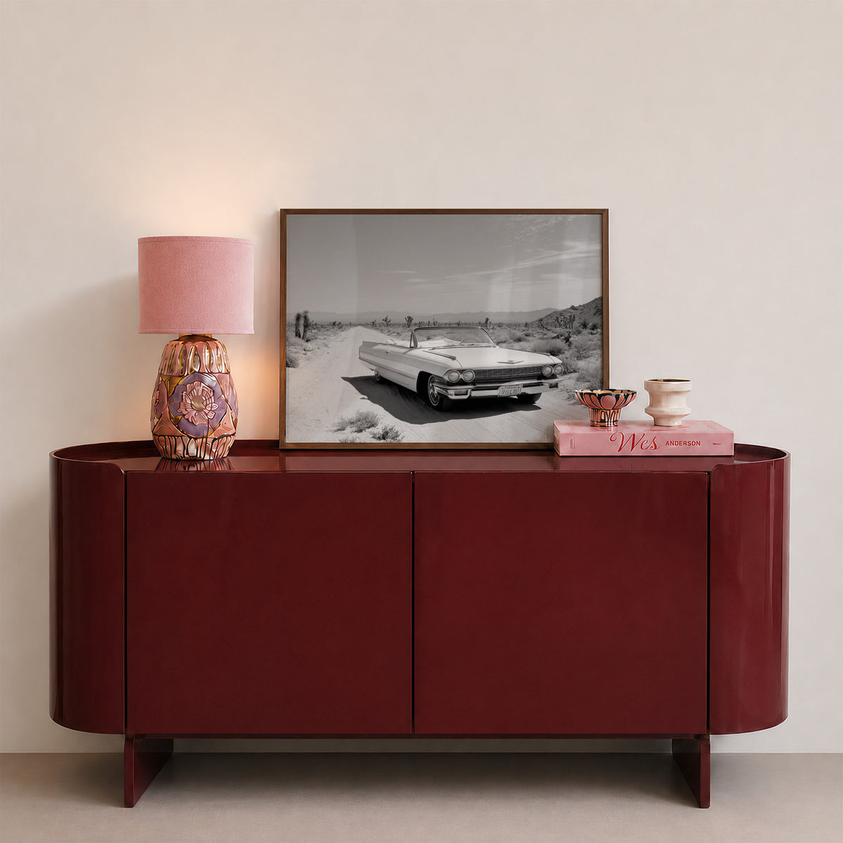 framed black and white Dust & Dreams poster print wall art sitting on red console with pink decor