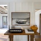 Framed black and white dust and dreams wall art  hanging in entryway above wooden table with keyboard and decor