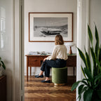 Framed black and white dust and dreams poster print hanging on wall above desk with a woman admiring below