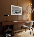 Modern home office with wooden desk, chair, lamp, and Framed black and white dust and dreams wall art  above desk