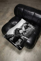Black leather armchair with Framed black and white freedom poster print on its seat.