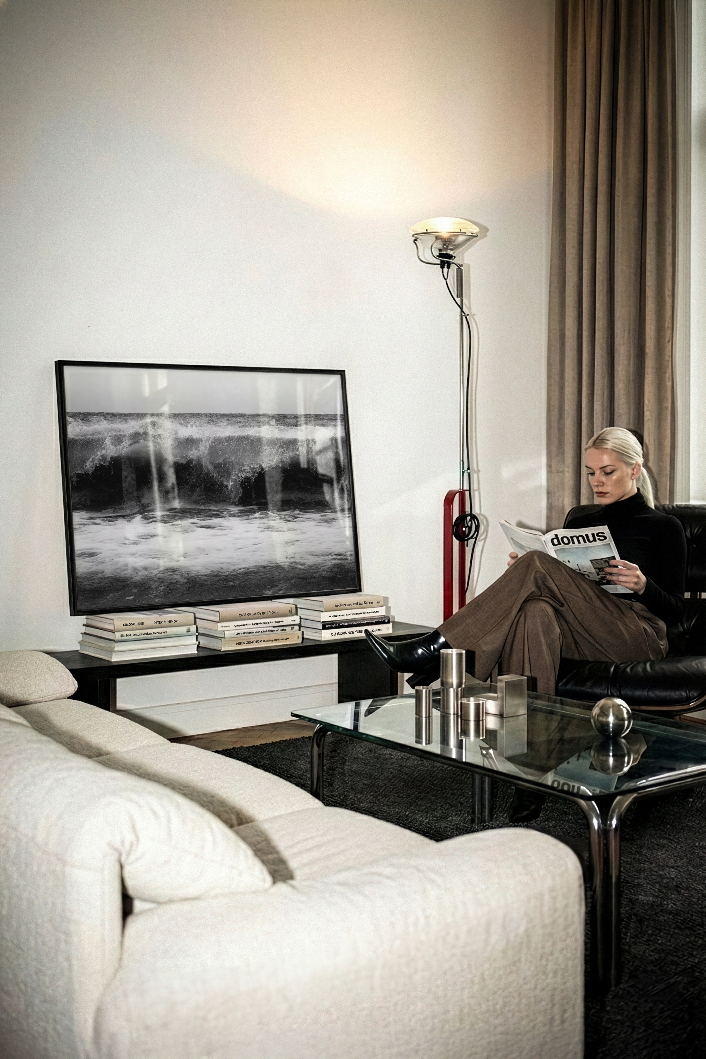 Modern living room with a woman reading a magazine, a large TV, and stylish decor.   framed black and white high tide poster print sitting on coffee table books leaning against the wall