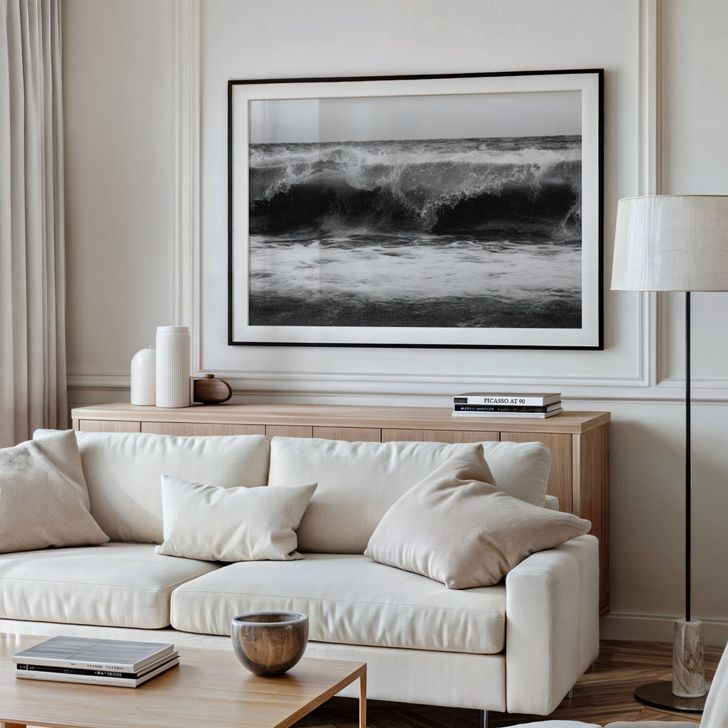 Modern living room with a white sofa, wooden coffee table, and framed black and white high tide poster print 