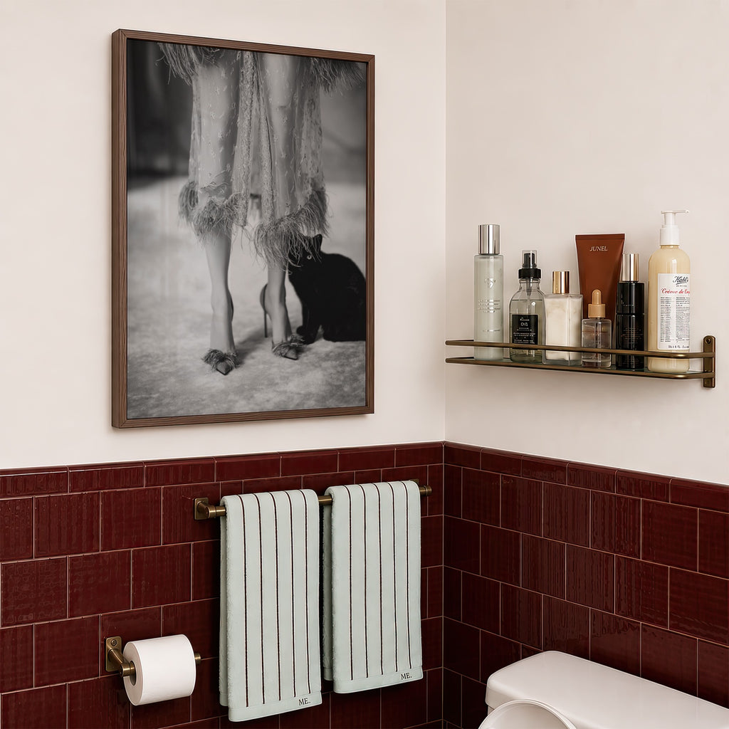 framed kitty kitty black and white poster print hanging in bathroom with red tile and gold shelf
