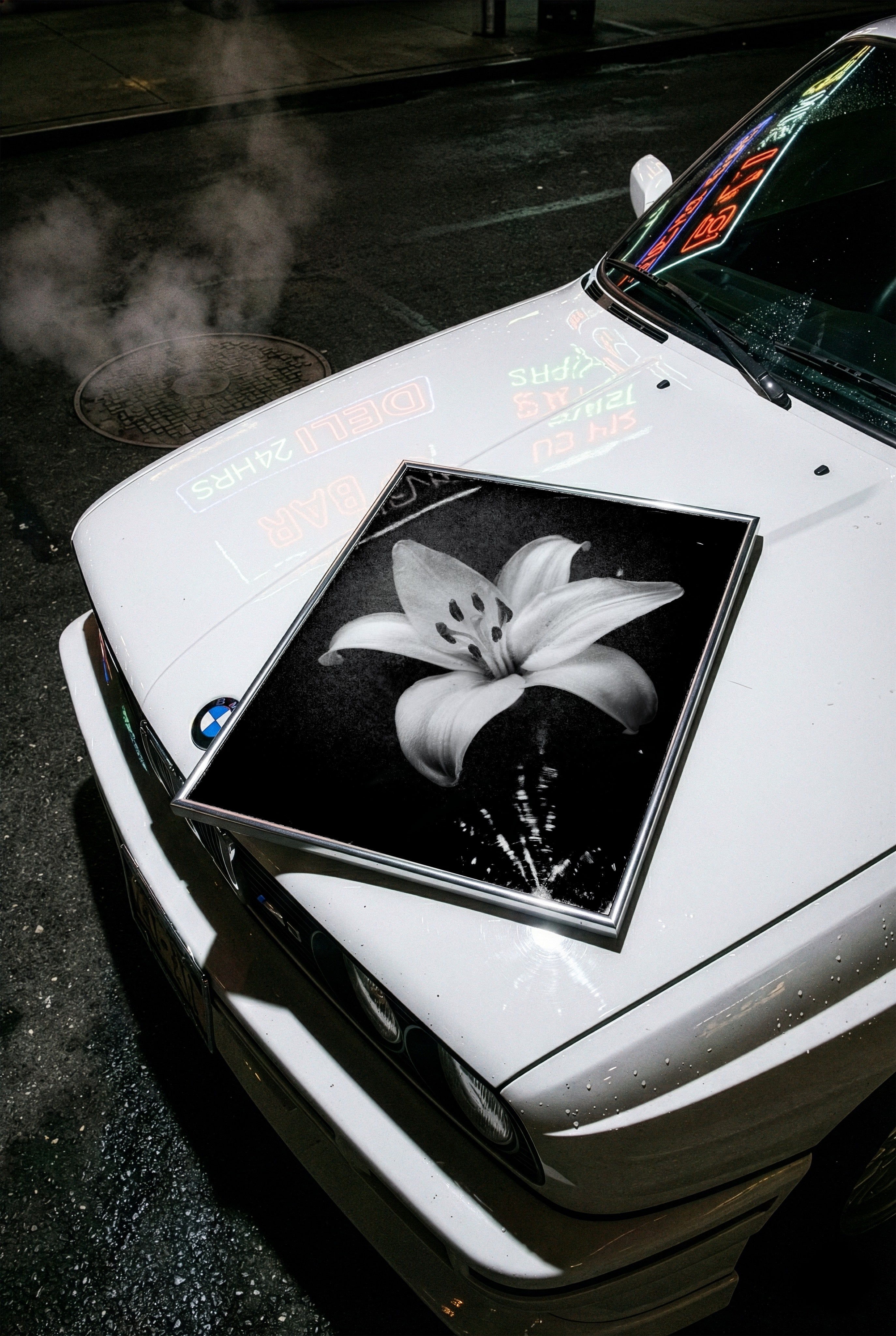 White car with a black and white flower poster on the hood