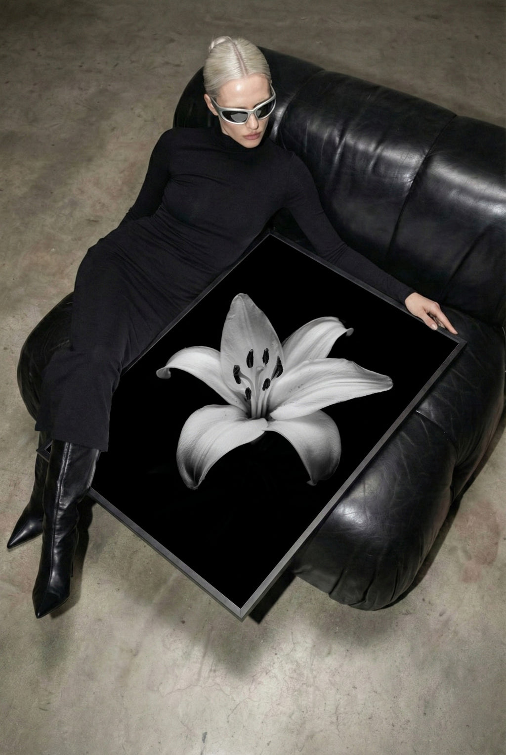 chic woman sitting next to framed black and white floral poster print on leather black chair