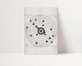 A square wall art print or canvas featuring a black atomic model design with a heart-shaped center on a light gray textured background, displayed against a white wall.