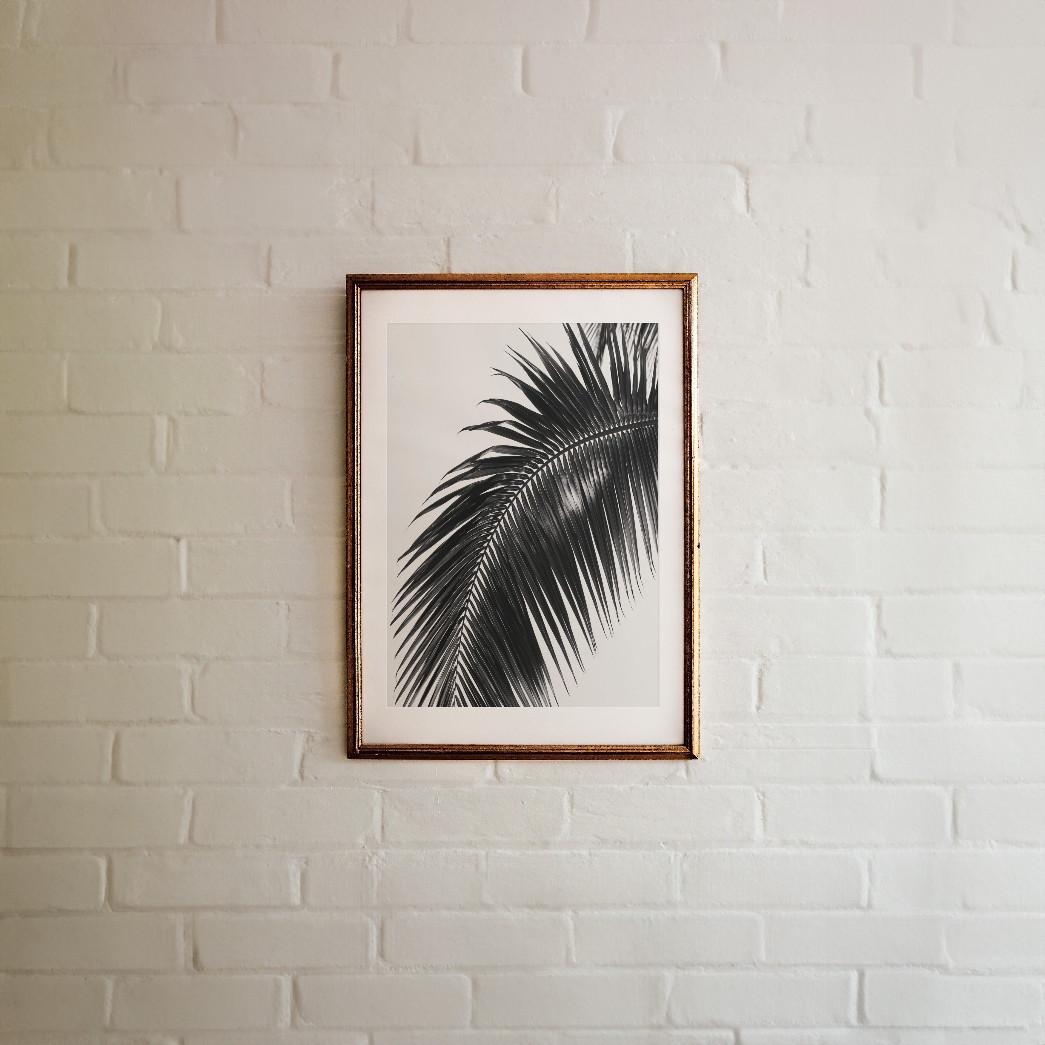 framed black and white paradise palm poster hanging on white brick wall