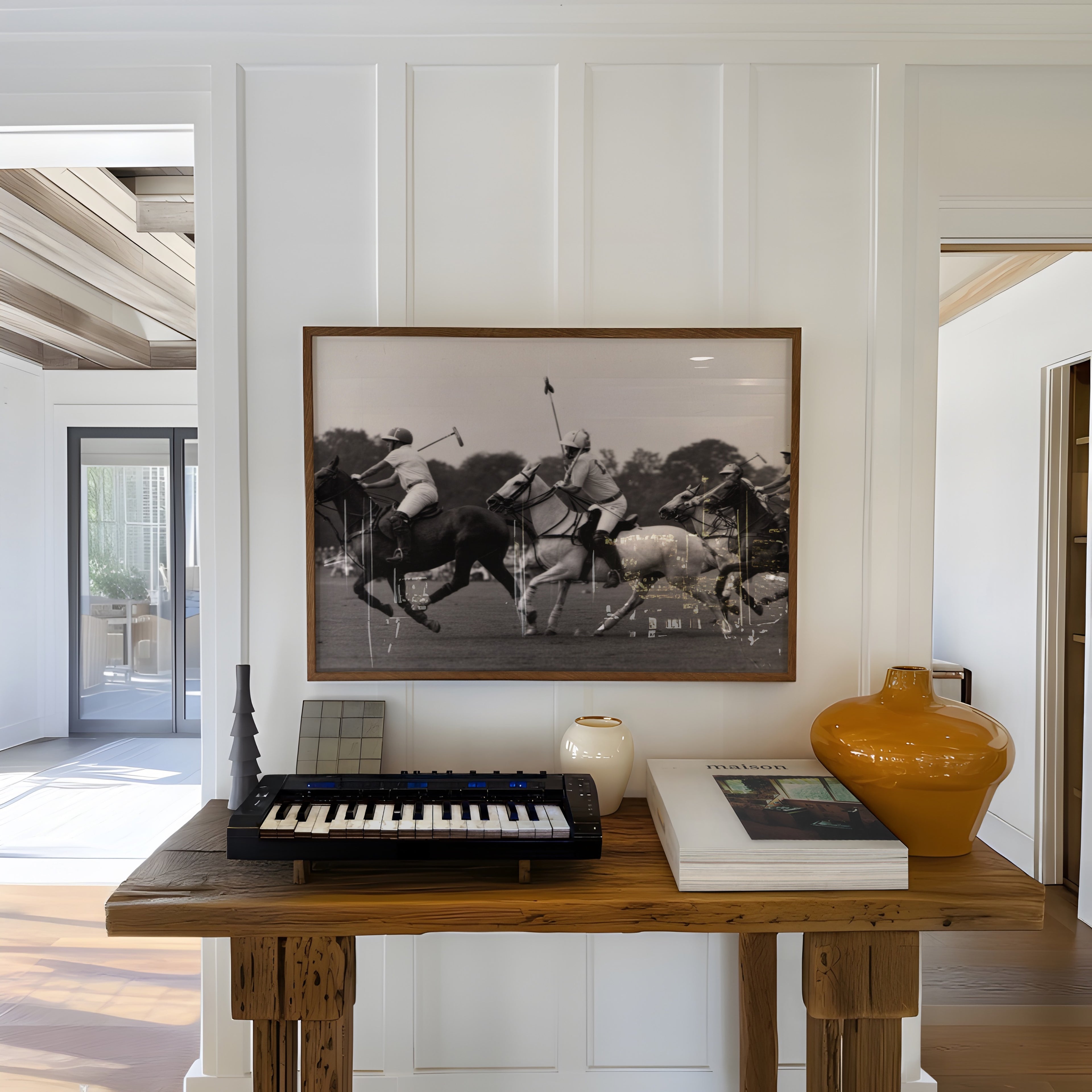 Wooden table with keyboard, books, and vases in a room with a framed black and white poster print hanging on the wall