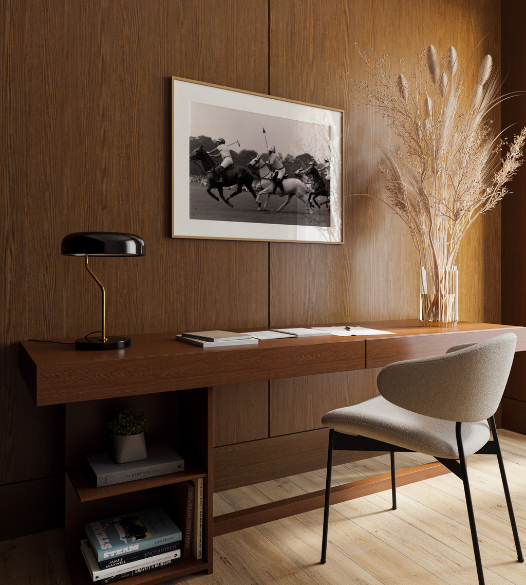 Modern home office with wooden desk, chair, and framed black and white polo club old money print hanging above desk