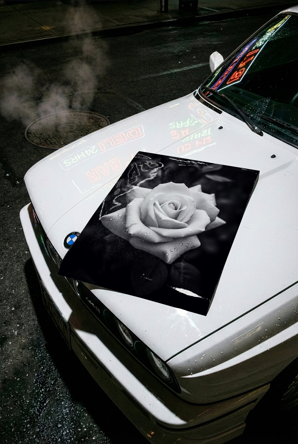 black and white floral poster print on hood of white car at night