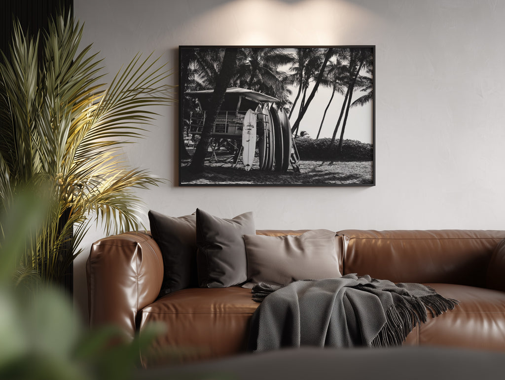 Brown leather sofa with decorative pillows and a blanket in a living room setting, featuring a Framed black and white Surfs Up poster print  on the wall.